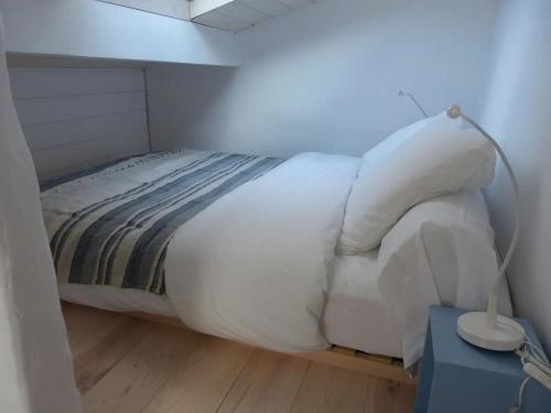 - un lit avec des draps et des oreillers blancs dans l'établissement APPARTEMENT COEUR DE LA STATION, à Mimizan