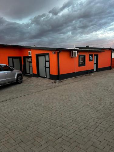 Un bâtiment orange avec une voiture garée devant. dans l'établissement Comfort Guesthouse, à Windhoek