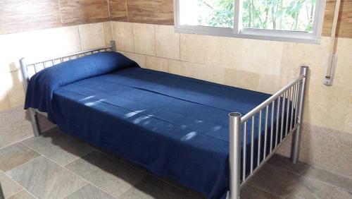 a bed with a blue sheets and a window at Cruz de Ferreira in Palas de Rei