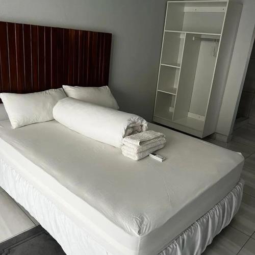 1 cama blanca grande en una habitación con espejo en Comfort Guesthouse en Windhoek