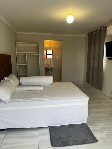 sypialnia z dużym białym łóżkiem w pokoju w obiekcie Comfort Guesthouse w mieście Windhuk