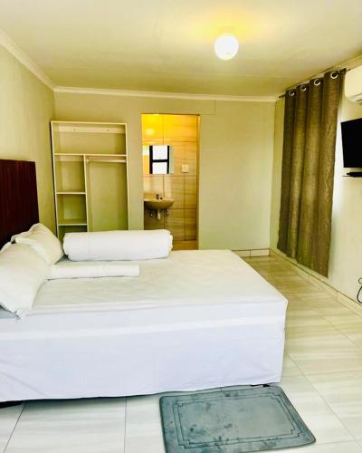 a bedroom with a large white bed and a bathroom at Comfort Guesthouse in Windhoek