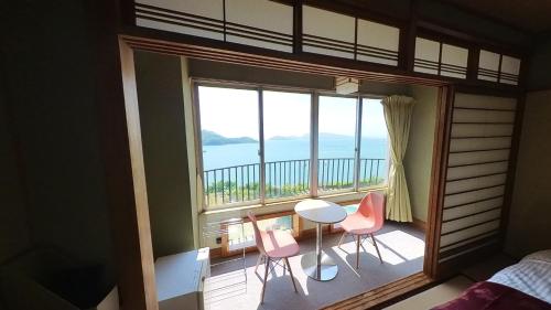 una camera da letto con balcone arredato con tavolo e sedie di HOTEL GREEN PLAZA SHODOSHIMA - Vacation STAY 46464v a Ikisue