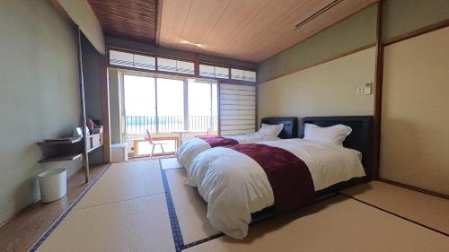 una camera da letto con un grande letto con una grande finestra di HOTEL GREEN PLAZA SHODOSHIMA - Vacation STAY 46464v a Ikisue