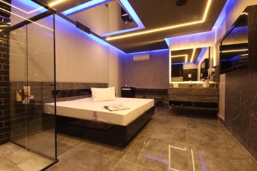 a bedroom with a bed and a bathroom with blue lights at Motel Deslize Limeira 1 in Limeira