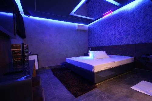 a bedroom with a bed with blue lights on it at Motel Deslize Limeira 1 in Limeira