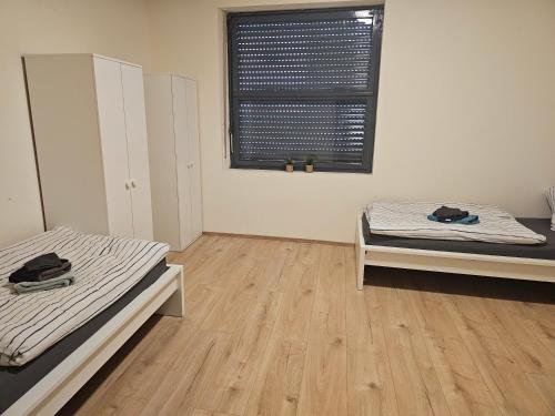 twee bedden in een kamer met houten vloeren en een raam bij Neu Modernisiert Work and Stay top moderne 3 Zimmer Wohnung 5 Betten in Geilenkirchen