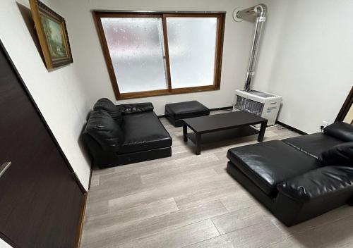 a living room with black leather furniture and a window at Ota Apartment - Vacation STAY 16060 in Otaru