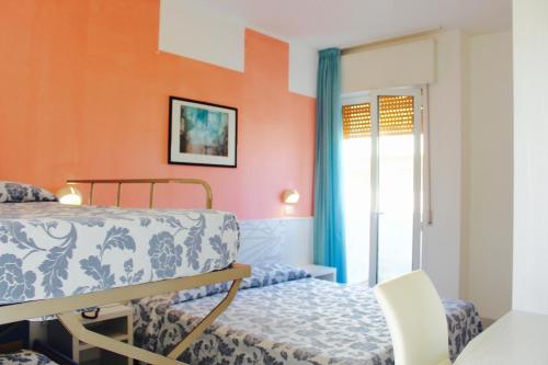 Schlafzimmer mit orangefarbenen Wänden, einem Bett und einem Fenster in der Unterkunft Hotel President in Cesenatico