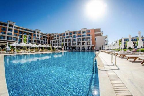 a large swimming pool with chairs and buildings at Premier Fort Apartment on Seafront in Sveti Vlas
