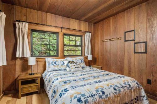 a bedroom with a bed with wooden walls and a window at Cedar Camp in Welches