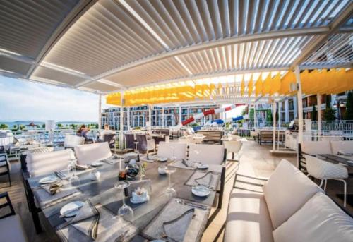 a restaurant with white tables and chairs and a view of the ocean at Premier Fort Apartment on Seafront in Sveti Vlas