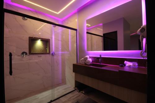 y baño con iluminación púrpura, lavabo y ducha. en Motel Deslize Limeira 2 en Limeira