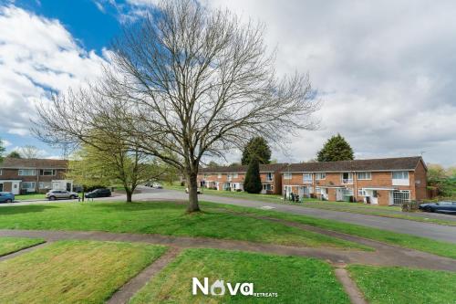 a tree in the grass next to a street at Luxury 3 Bed Apartment, Private Parking BHX JLR NEC HS2 in Solihull