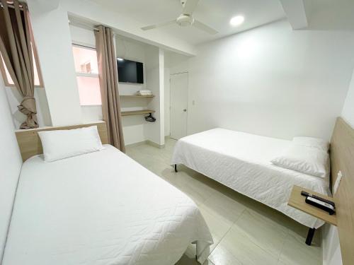 a bedroom with two beds and a tv on the wall at Casa Victoria in Montería