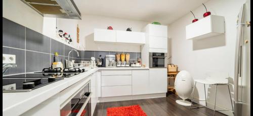 een keuken met witte kasten en een rood tapijt bij Appartement petit déjeuner offert plus ménage in Clermont-Ferrand