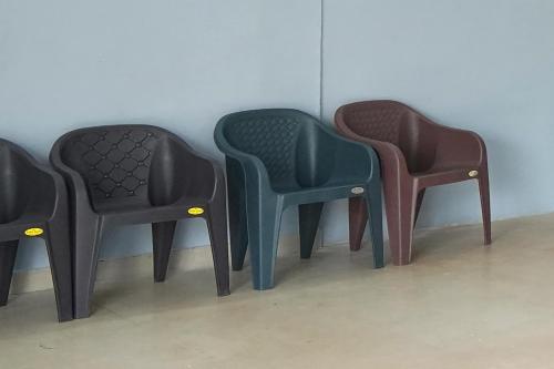 three different colored chairs sitting next to a wall at Hotel O Shining Star in Bhilai