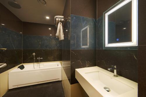 La salle de bains est pourvue d'un lavabo, d'une baignoire et d'une fenêtre. dans l'établissement Hotel Merrytale, à Kurinjippādi