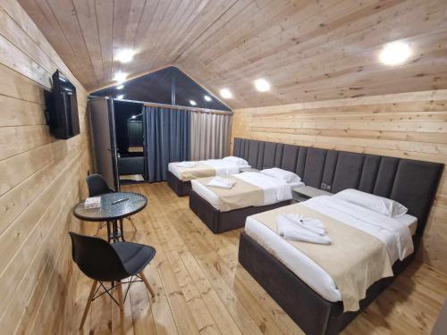 a hotel room with two beds and a table and chairs at NICE HOUSE HOTEL Meghri in Meghri