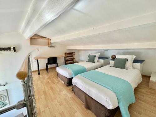 two beds in a room with a desk at Le St Julien Terrasse vue mer exceptionnelle in Menton