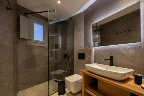 a bathroom with a sink and a shower and a toilet at Nastram Suites Oia in Oia