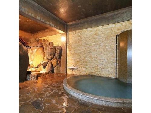a large tub in a room with a stone wall at Houraku - Vacation STAY 23297v in Kamikawa