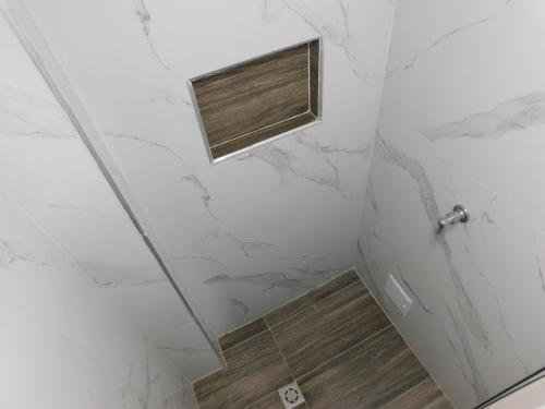 a shower with white marble walls and a window at El Velero Apartamentos By DANP in Santa Marta
