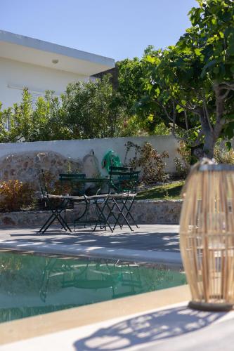 two green benches sitting next to a swimming pool at RELAXING POOL HOUSE IN LAGONISI 2 in Kalívia Thorikoú