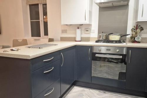 a kitchen with blue cabinets and a stove at Liam's place in Manchester