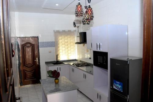 kuchnia z białymi szafkami i czarną lodówką w obiekcie FANZMA APARTMENTS w mieście Abudża
