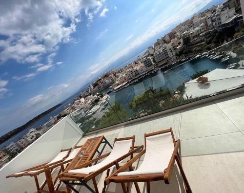 a group of chairs on a balcony overlooking the water at Gioma Luxury Suites - Lake View - Jacuzzi in Agios Nikolaos