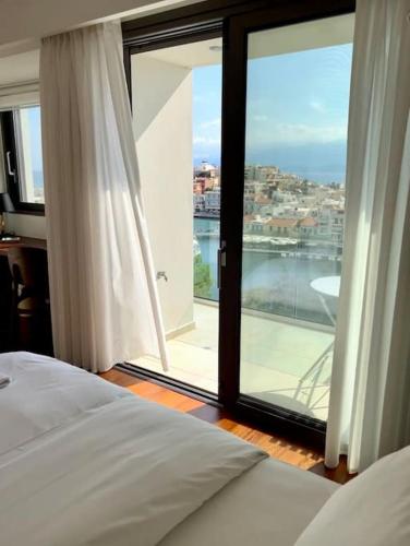 a bedroom with a bed and a large glass window at Gioma Luxury Suites - Lake View - Jacuzzi in Agios Nikolaos