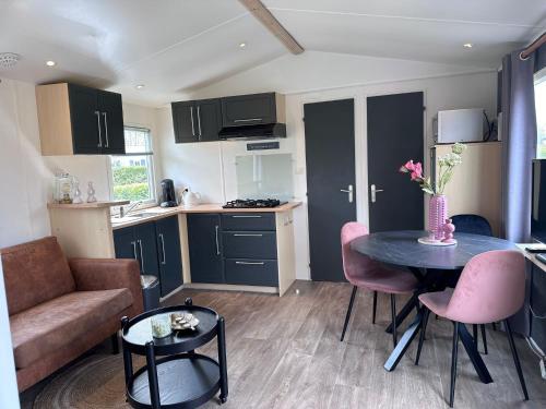 uma cozinha e uma sala de estar com mesa e cadeiras em Captivating chalet with a microwave, near the Wadden Sea em Tzummarum