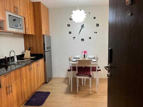 a kitchen with a table and a clock on the wall at The Elevated Abode - ComfyCosy 1-br at The Loop in Cagayan de Oro