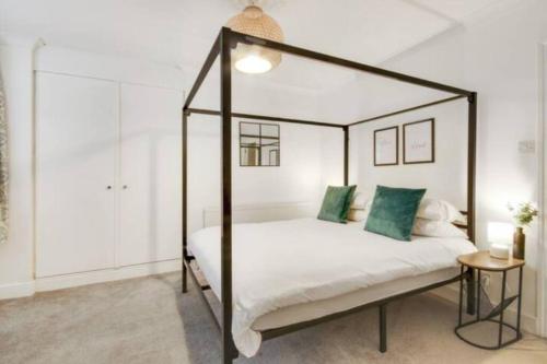 a bedroom with a canopy bed with green pillows at Central 2 bedroom garden flat with free parking in Royal Tunbridge Wells