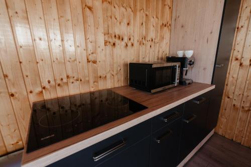 a kitchen with a microwave on a counter with wooden walls at CAVO VILLAGE- Cabins Rental Băile 1 Mai in Rontău