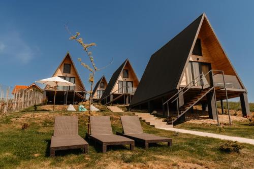 a row of cottages on top of a hill with chairs at CAVO VILLAGE- Cabins Rental Băile 1 Mai in Rontău