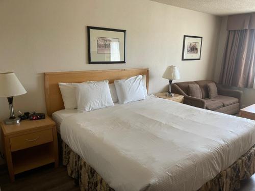 a hotel room with a large bed and a couch at Chelsea Inn in Coquitlam