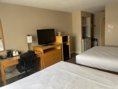 a hotel room with a bed and a desk with a television at Chelsea Inn in Coquitlam