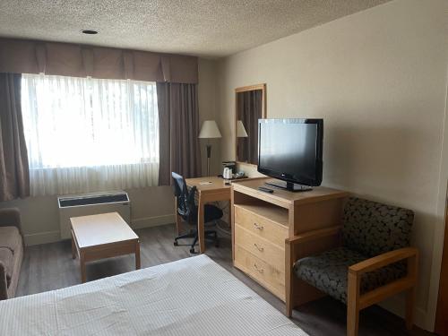 a hotel room with a bed and a desk with a television at Chelsea Inn in Coquitlam