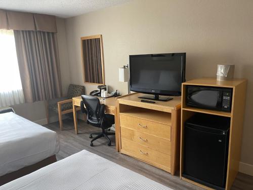 a hotel room with a television and a desk with a bed at Chelsea Inn in Coquitlam