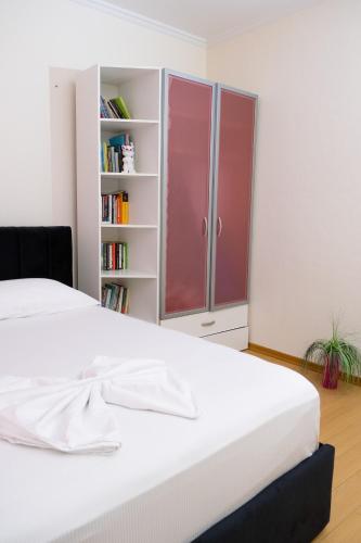 a white bed in a room with a book shelf at ALBJONA GUESTHOUSE TIRANA in Tirana