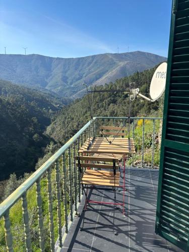 a picnic table on a balcony with mountains in the background at White House in Piódão