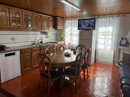 eine Küche mit einem Tisch und Stühlen sowie einem TV in der Unterkunft White House in Piódão