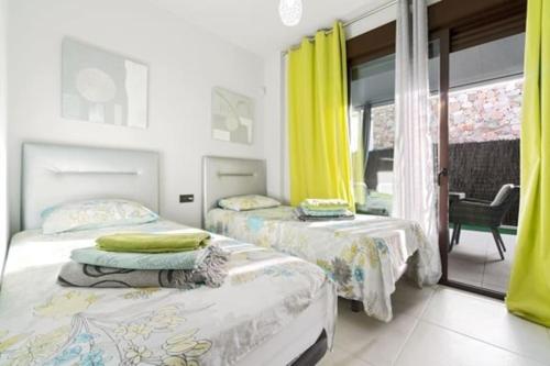 two beds in a room with yellow curtains at VillaHeLena in Orihuela Costa