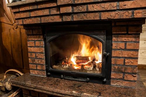 a brick fireplace with a fire in it at Chatka Pod Laskiem - Domki w górach in Soblówka