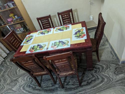 a dining room table with chairs and paintings on it at Ushuaia- Entire villa, nestled in nature's embrace in Navelim