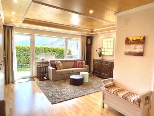 ein Wohnzimmer mit einem Sofa und einem großen Fenster in der Unterkunft Sunny-Nest, Garden Apartment in Leukerbad