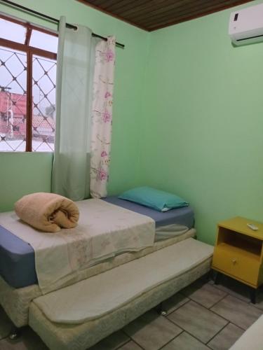two twin beds in a room with a window at Hospedaria das Azaleias in Novo Hamburgo
