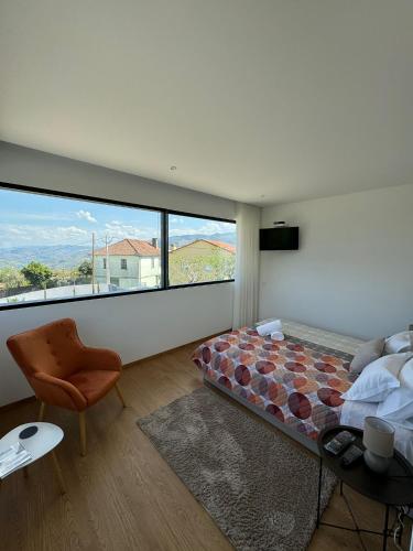 a bedroom with a bed and a chair and a large window at Douro - Quinta das Manas - Baião in Alcarias